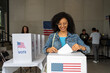© Alan - portrait of a young african american woman voting in the us election, placing vote ballot in the polling box, vote in America. Concept of usa choice, democracy and freedom