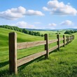 © Owl.Studio - Wooden fence lined across green meadow under blue sky with fluffy clouds.