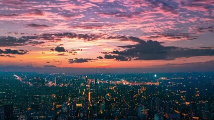 Poster - A breathtaking sunset paints the sky with vibrant hues, casting a warm glow over the bustling city below as lights begin to twinkle in the twilight.
