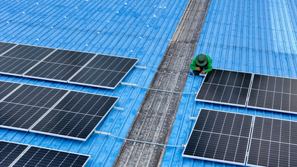 top aerial of engineer men inspects construction of solar cell panel or photovoltaic cell at roof top. Industrial Renewable energy of green power. factory at urban area. worker working on tower roof.