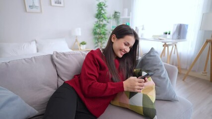 Wall Mural - Asian beautiful woman sitting on sofa and swipe mobile phone in house.