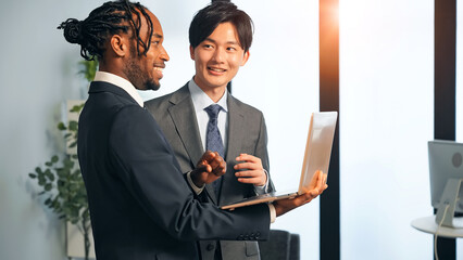 Group of multinational business people discussing business management while looking at laptop in office