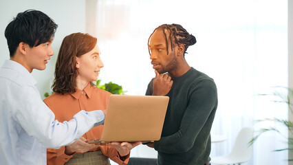 Poster - Multinational people talking while looking at a laptop in an office
