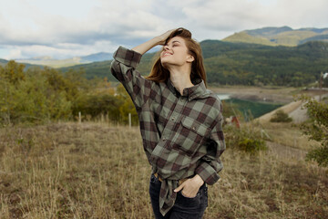 Poster - A woman in a plaid shirt enjoying the scenic view of mountains in a peaceful field landscape