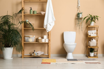 Wall Mural - Interior of modern restroom with white toilet bowl, houseplants and shelving unit near beige wall