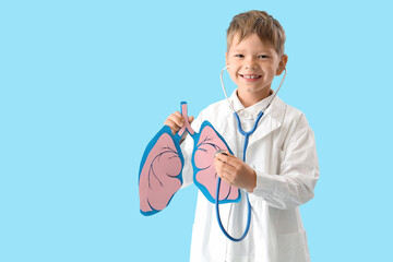 Little doctor with stethoscope and paper lungs on blue background