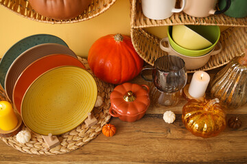 Different dishes, autumn decor and candles on wooden table in kitchen