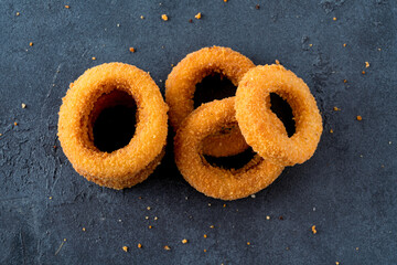 Wall Mural - Fried onion rings with mozzarella or plain. Delicious onion rings on black background	
