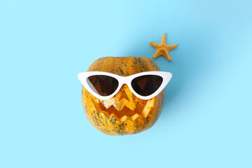 Halloween pumpkin with sunglasses and starfish on blue background