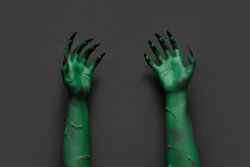 Wall Mural - Green hands of witch with claws on black background. Halloween celebration