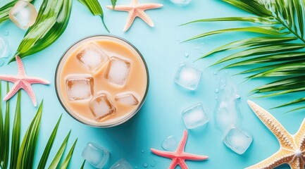 A glass of cold coffee with ice cubes on the table, surrounded by green palm leaves and starfish