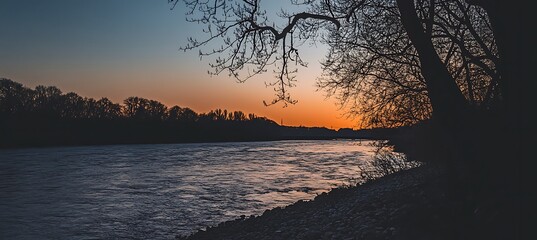 Wall Mural - A serene, riverbank at sunset with a clear sky and a large area for text