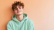 © Роберт Гастон - Portrait of Young Man in Mint Green Hoodie with Playful Smile Against Light Peach Wall
