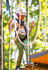 brave little boy in helmet climbing at adventure park in autumn season. Work out concept