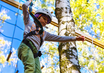 brave little boy in helmet climbing at adventure park in autumn season. Work out concept