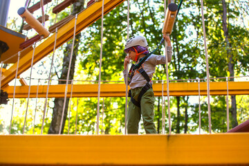 brave little boy in helmet climbing at adventure park in autumn season. Work out concept