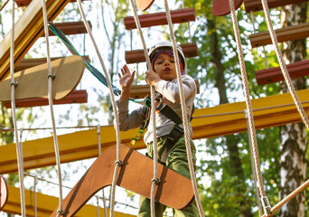 brave little boy in helmet climbing at adventure park in autumn season. Work out concept