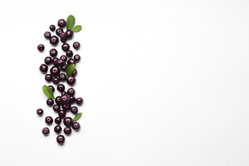 Ripe acai berries and leaves on white background, flat lay. Space for text