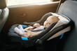 © Anastasiya - A young baby is comfortably secured in a car seat, gazing curiously while bright sunlight streams through the vehicle's window, creating a warm atmosphere.