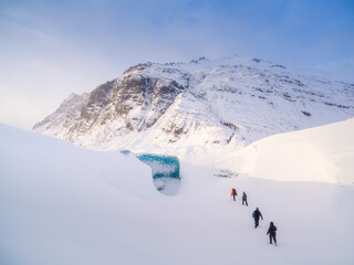 Wall Mural - team in front of the entrance to an ice cave in iceland. a walk on the glacier. high mountains and c