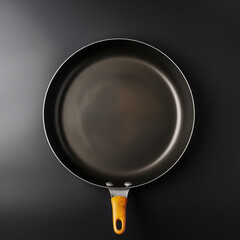 Top View Of Black Nonstick Frying Pan With Yellow Handle On Dark Background