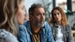 © Anna - A middle-aged man with a pensive expression participates in a group therapy session