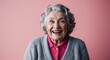© Arceli - Joyful elderly Caucasian woman with grey curls wearing cardigan on plain pink background