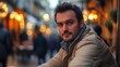 © Prostock-studio - A man enjoys a moment of relaxation at a cafe, surrounded by softly lit shops and pedestrians, capturing the essence of a lively evening in a quaint European street.