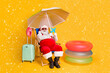 © deagreez - Full size photo of grey white hair bearded santa claus relax chill chaise-lounge x-mas christmas hold paper card plane wear red sunglass cap hat isolated yellow color background