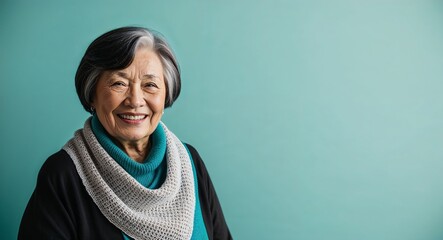 Wall Mural - Cheerful elderly Black woman with short grey hair wearing shawl on plain turquoise background