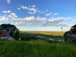 Scenic view of lush landscape with river and vast sky and the ski lift not work in summer. Panorama of nature captured from hilltop during serene summer day.