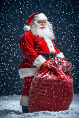 Canvas Print - A man dressed as Santa Claus holding a large bag of presents