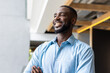 © WavebreakMediaMicro - Smiling african american man in blue shirt standing confidently in modern office environment