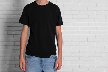 Sticker - Teenage boy wearing black t-shirt near white brick wall, closeup. Space for text