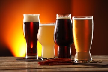 Wall Mural - Glasses with different types of beer and snacks on wooden table against color background