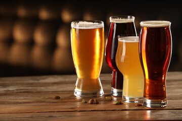 Sticker - Glasses with different types of beer and pistachio nuts on wooden table indoors, space for text