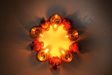 Wall Mural - Diwali celebration. Diya lamps and beautiful flowers on dark textured surface, flat lay. Space for text