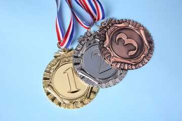 different medals on light blue background, flat lay