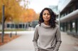 © Markus Schröder - Portrait of a tender indian woman in her 40s dressed in a comfy fleece pullover in front of modern university campus background