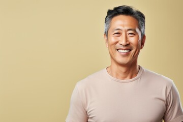 Wall Mural - Portrait of a smiling asian man in his 50s sporting a breathable mesh jersey in front of pastel or soft colors background