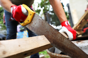 Canvas Print - Man sawing wooden plank in backyard, closeup