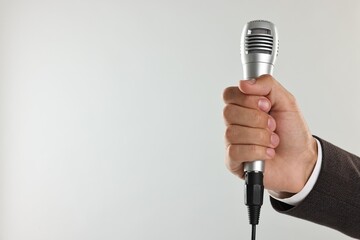 Wall Mural - Man with microphone on light grey background, closeup. Space for text