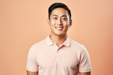 Poster - Portrait of a happy asian man in his 20s wearing a breathable golf polo in pastel or soft colors background