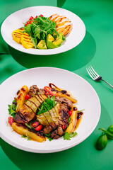 Two plates with gourmet salads on a green table