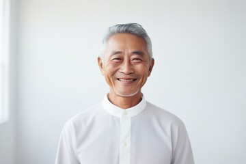 Canvas Print - Portrait of a grinning asian man in his 60s donning a trendy cropped top over minimalist or empty room background