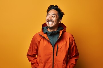 Portrait of a smiling asian man in his 30s wearing a functional windbreaker on solid color backdrop