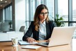 © ibhonk - Businesswoman working at a desk with a laptop and notepad