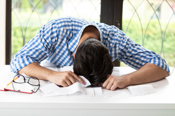 Wall Mural - Close up of unhappy man sitting at the table, stressed and confused by calculate expense from invoice or bills, have no money to pay mortgage or loan. High prices and spending money concept