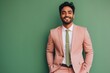 © Markus Schröder - Portrait of a grinning indian man in his 20s wearing a professional suit jacket on solid pastel color wall