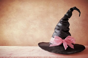 Magical black witch hat with pink ribbon on vintage background